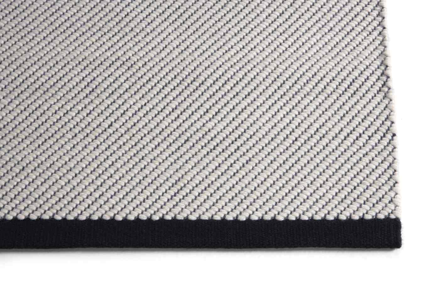 Detailaufnahme des Bias Rug Tint Teppichs in Schwarz-Weiß mit diagonaler Webstruktur. Hochwertiger Teppich für Wohnräume.