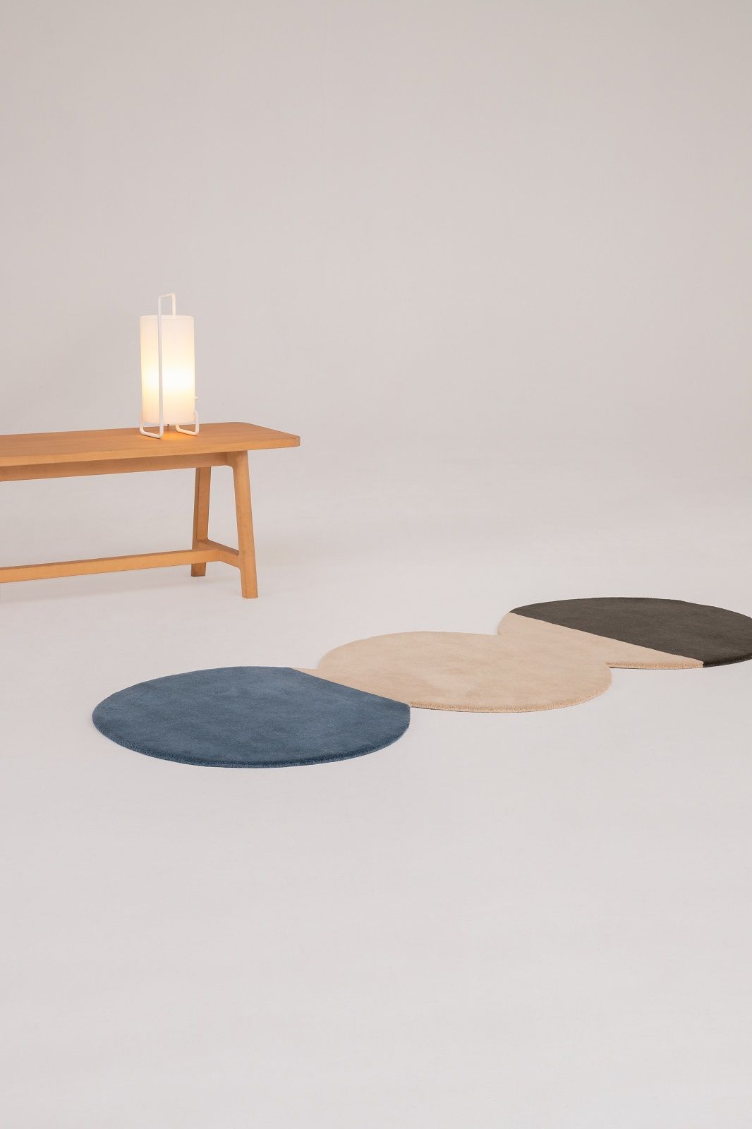 Drei runde Nanimarquina Teppiche in Blau, Beige und Schwarz auf weißem Hintergrund.