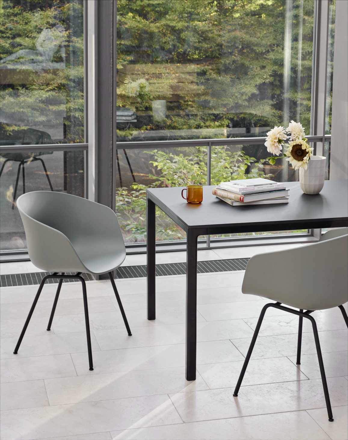 About A Chair AAC26 Stuhl in Slate Blue am Esstisch mit schwarzen Beinen.