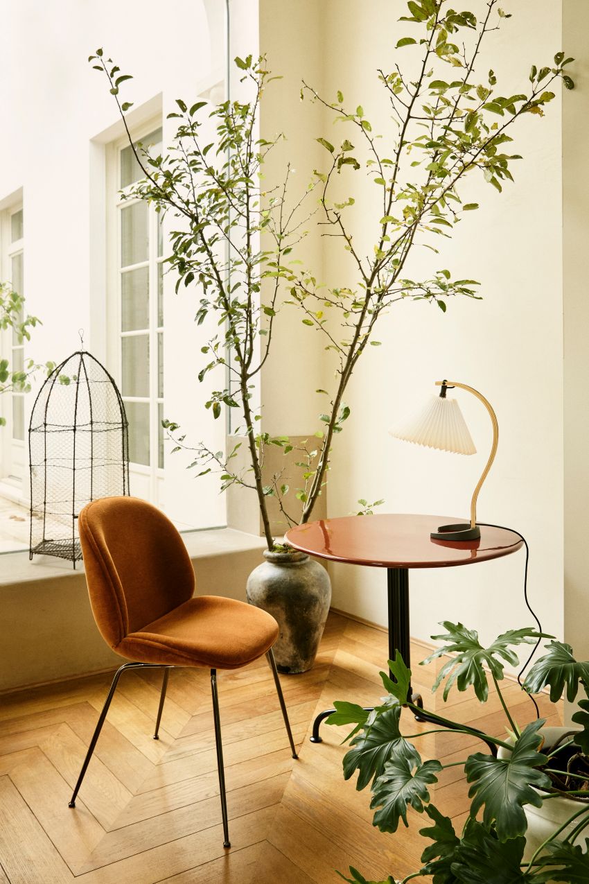 Nahaufnahme einer Timberline Tischleuchte von Gubi auf einem roten Beistelltisch in einem stilvollen Interieur.