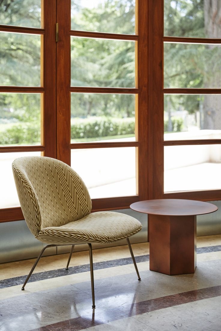 Epic Coffee Table Table basse 60 Earthy Red Acier Gubi Epic Coffee Table Couchtisch 60 Earthy Red Stahl Gubi neben einem Stuhl vor einem Fenster.