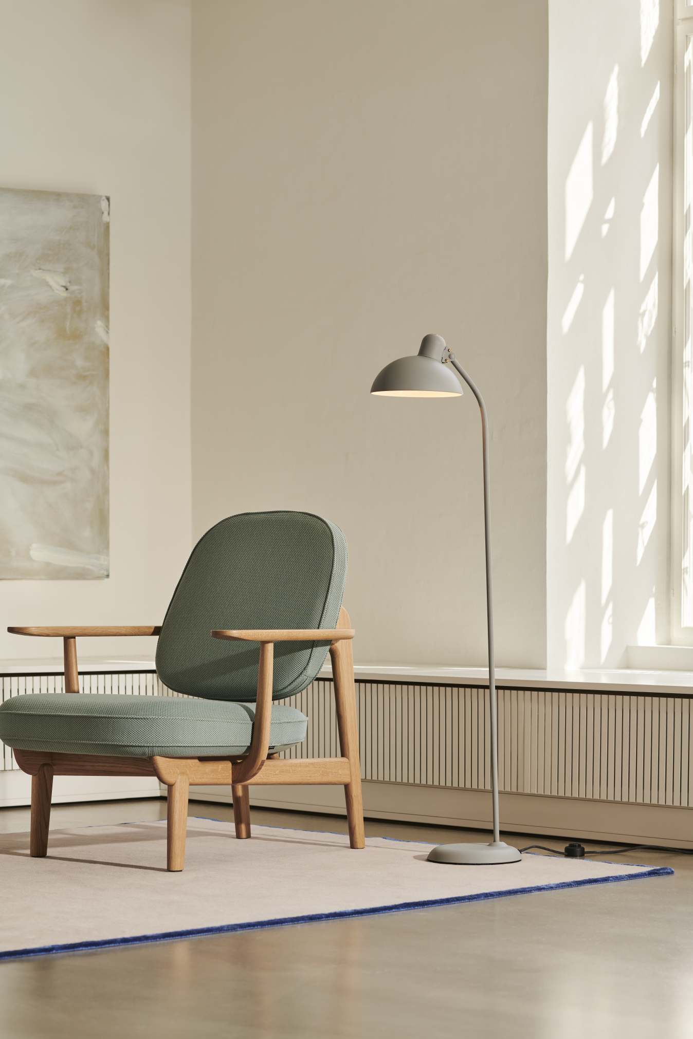 Helle, graue Kaiser Idell Stehleuchte 6556 F von Fritz Hansen neben einem Sessel.