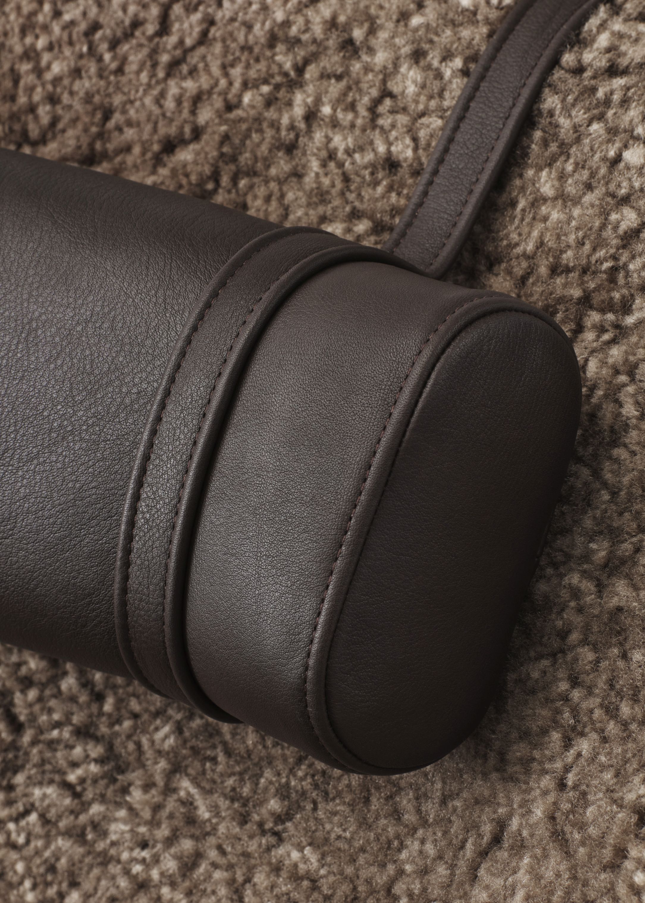 Braune Leder Nackenstütze von Lodge Vipp, Detailaufnahme auf einem Teppich. Komfort und Design.