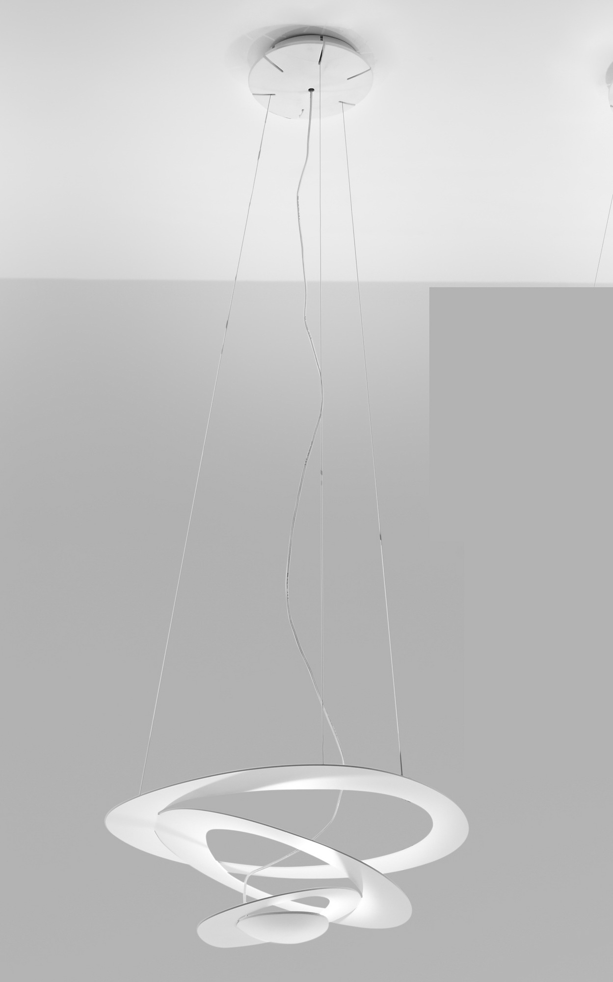 Weiße Pirce Micro LED Pendelleuchte von Artemide mit filigranen, geschwungenen Formen und warmweißem Licht.