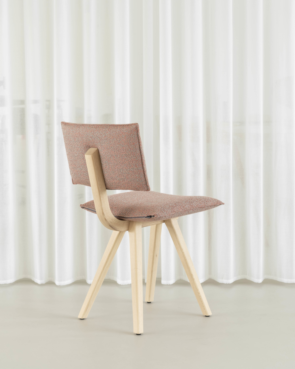 Trave Stuhl von Magis mit gepolstertem Sitz und Rückenlehne, helles Holzgestell vor weißem Vorhang.