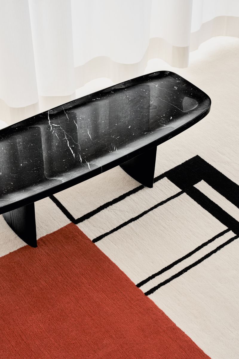 Nahaufnahme des Classicon Matéria Beistelltisches mit Marmorplatte Nero Marquina auf einem gemusterten Teppich.