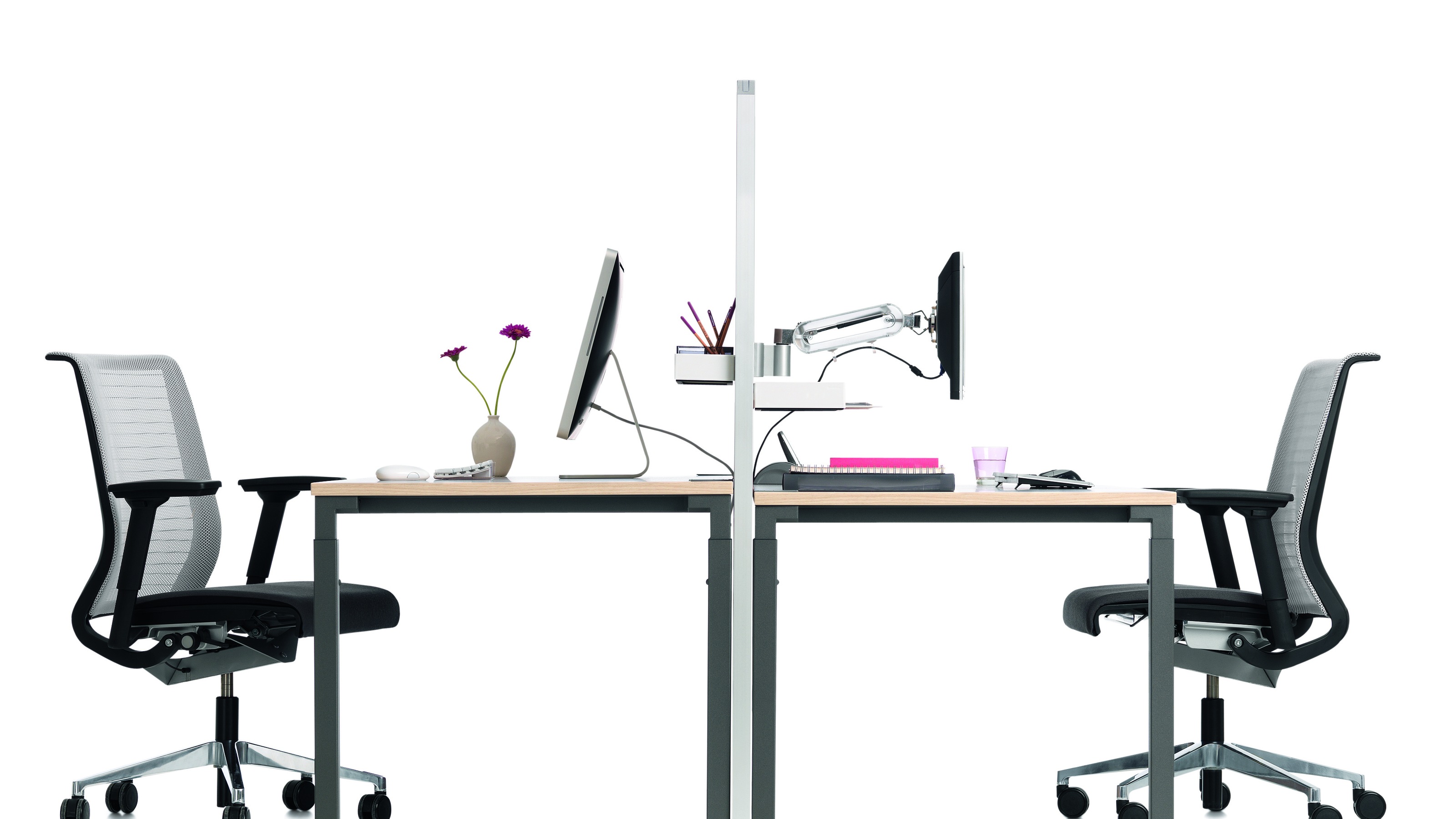 Kalidro Schreibtisch von Steelcase, höhenverstellbar, mit Bürostuhl, Monitor und Büromaterialien auf hellem Hintergrund.