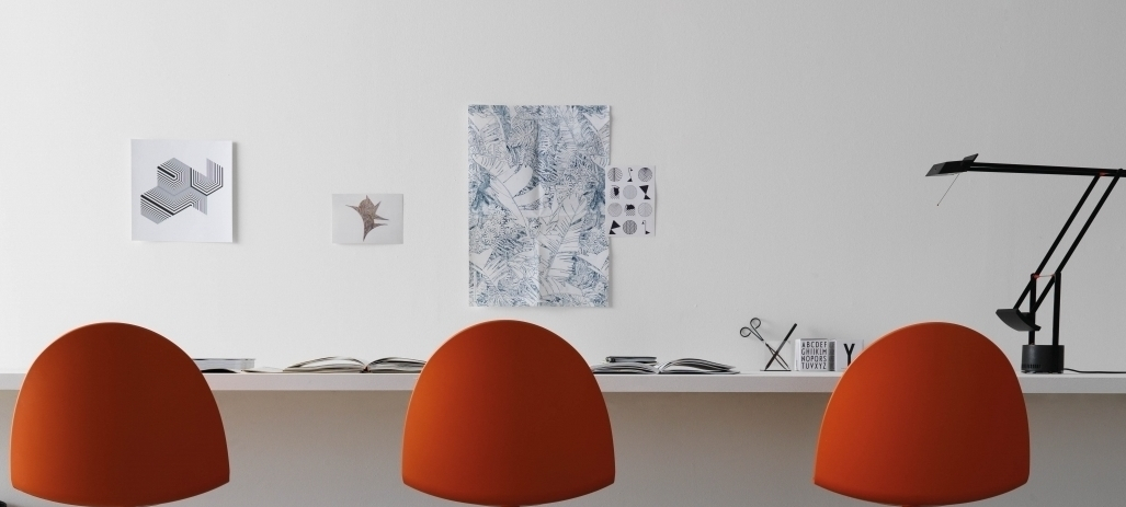 Camel Chaise Segis orange Drei orangefarbene Camel Stühle von Segis stehen an einem Schreibtisch in einem minimalistischen Büro.