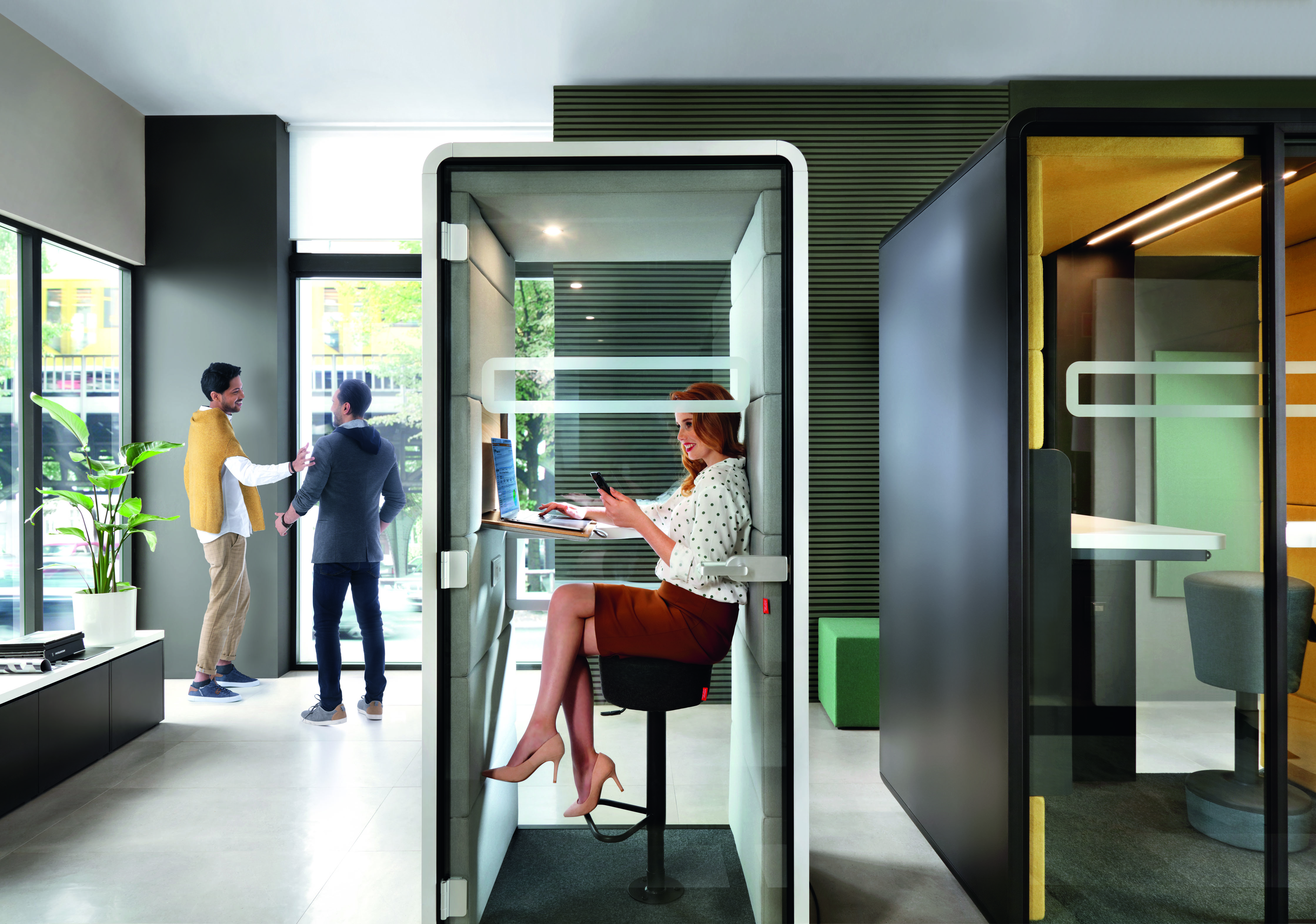 Frau arbeitet im HushPhone Meetingbox von Mikomax. Büro Arbeitsplatz mit Schreibtisch und Stuhl.