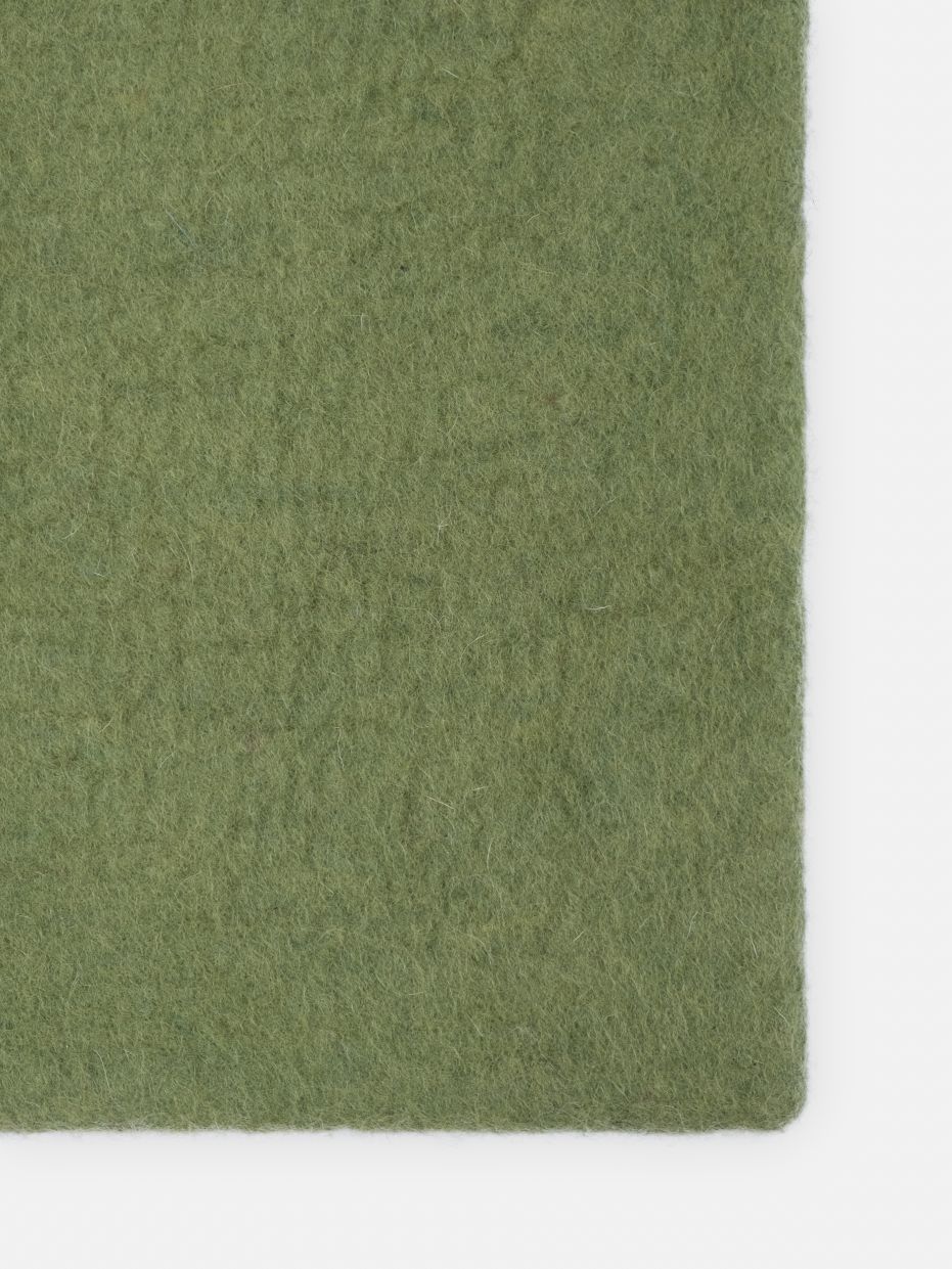 Detailaufnahme des grünen myfelt Kaspar Filzteppichs, rechteckig, für Wohnräume und Bodenbeläge.