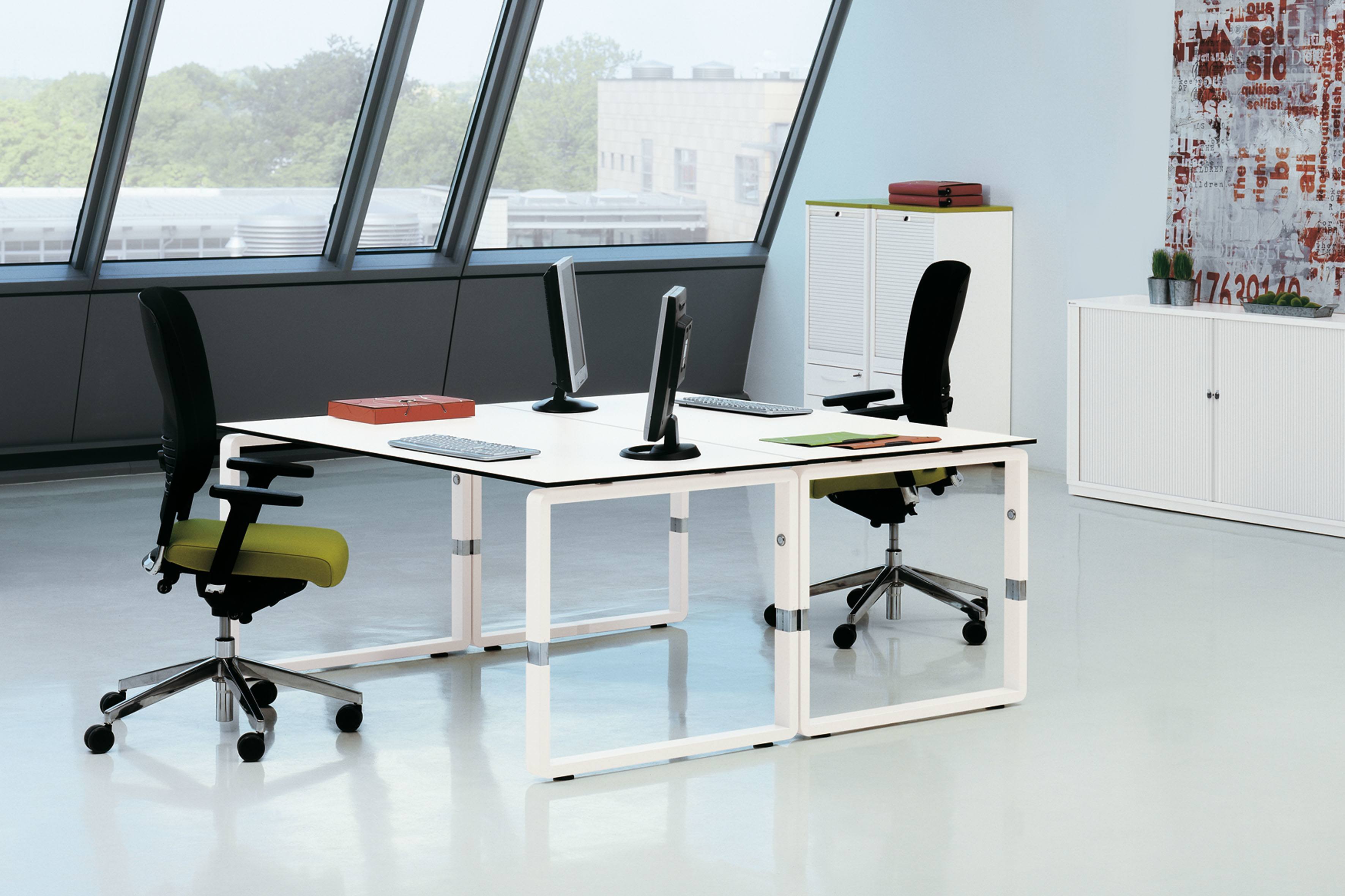 Heller Büroraum mit Palmberg Besprechungstisch in Ellipsenform, ausgestattet mit Monitoren und Bürostühlen.