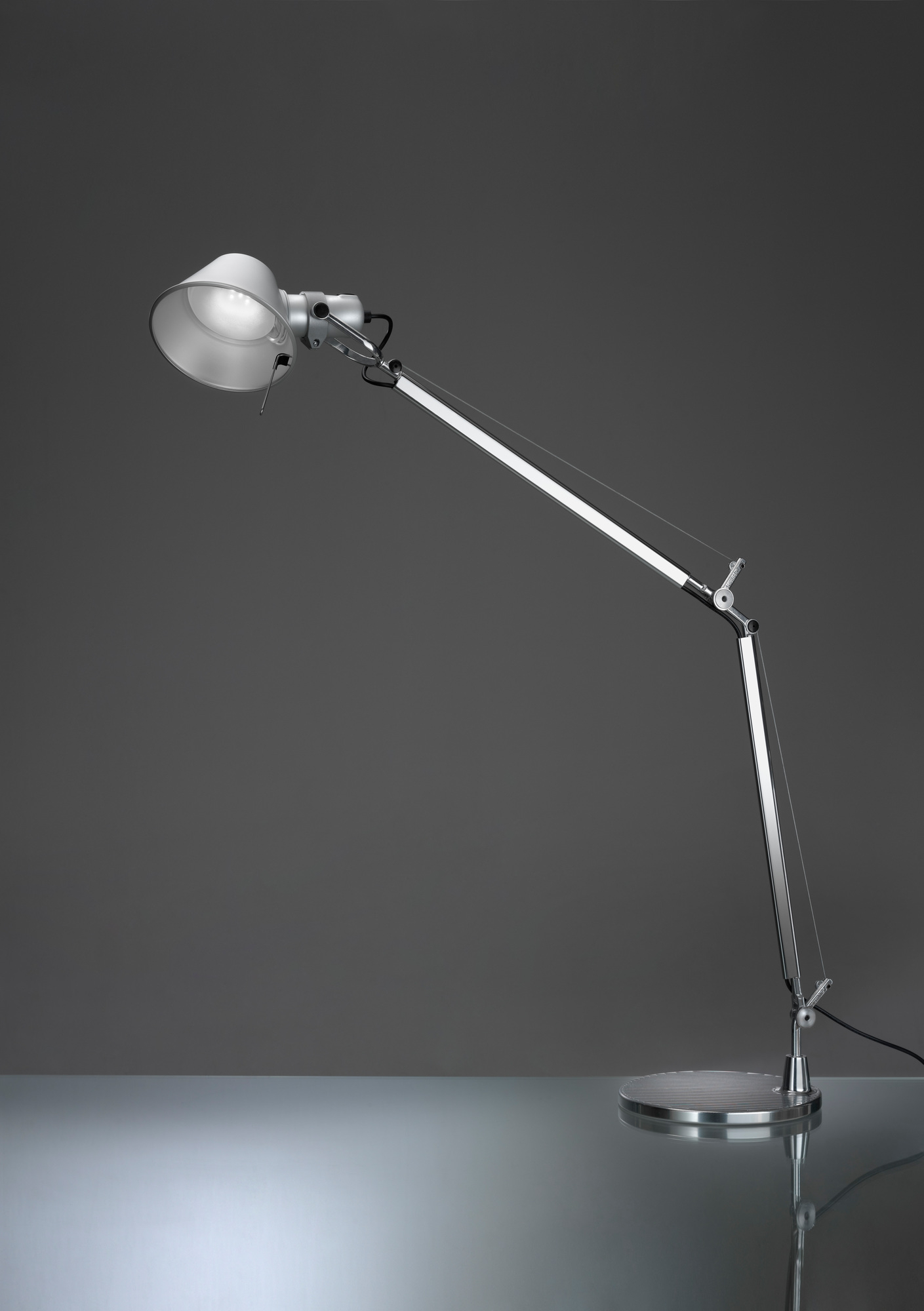 Nahaufnahme der Artemide Tolomeo Tischleuchte mit schwarzem Fuß, flexiblem Arm und hellem Licht.