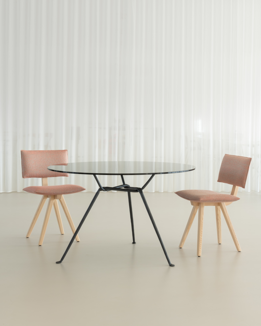 Zwei Trave Upholstered Chair Stühle von Magis mit einem runden Tisch vor einem weißen Vorhang.