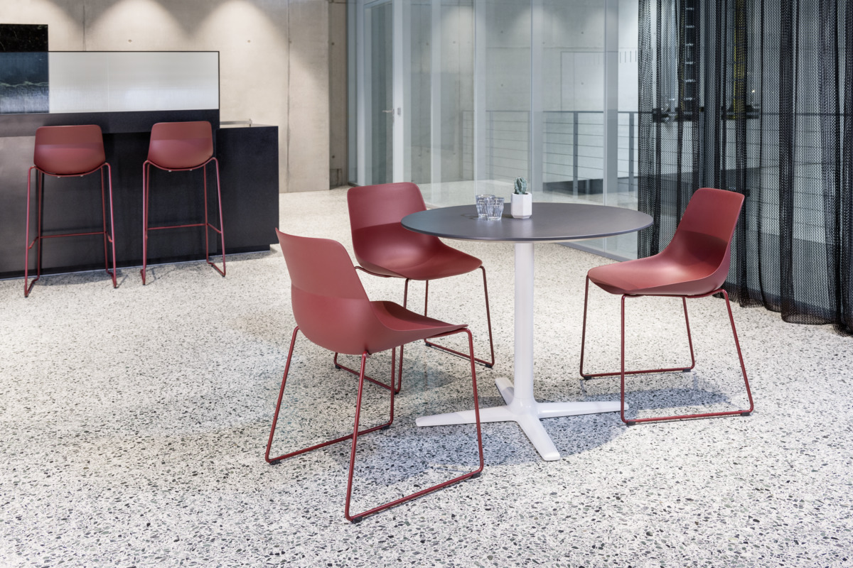 Rote Brunner Crona Light Kufenstühle um einen runden Tisch, moderne Büromöbel für Konferenzräume.