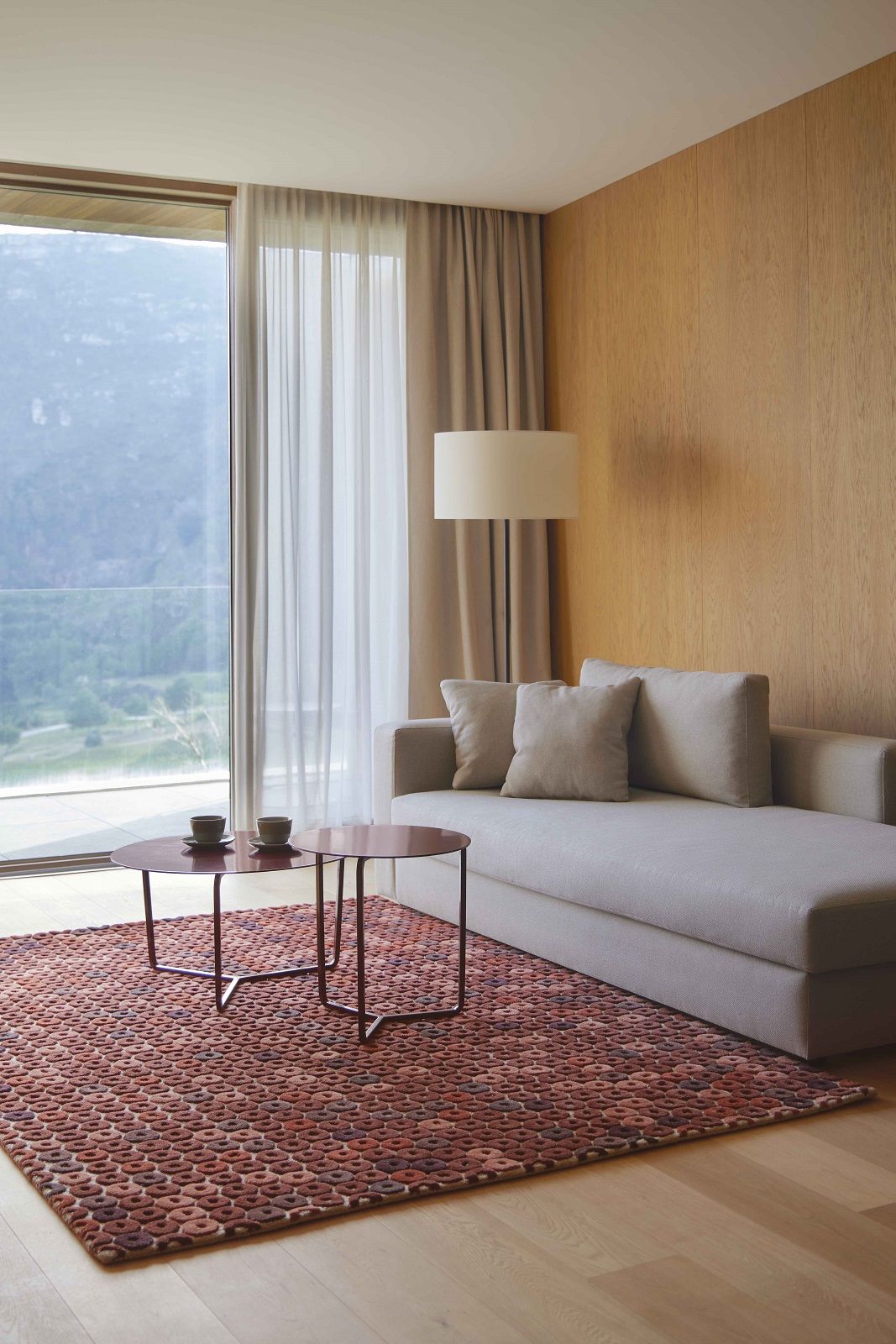 Chimos Rug Teppich Gan: Wohnzimmer mit modernem, gemusterten Teppich in warmen Erdtönen und minimalistischer Einrichtung.