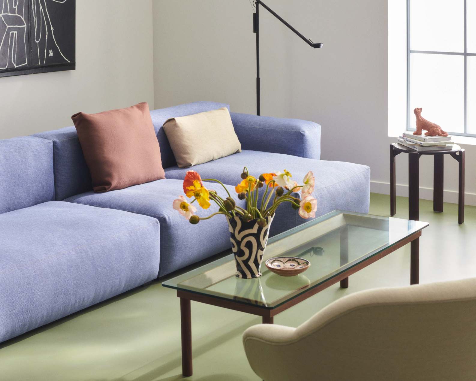 Blaues Mags Soft Sofa von Hay mit Kissen und Glas-Couchtisch im modernen Wohnzimmer.