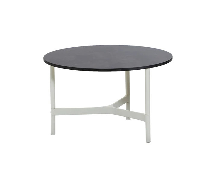Cane-Line Twist Beistelltisch Medium in Weiß mit runder, dunkler Tischplatte und filigranem Aluminiumgestell.