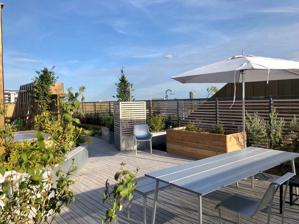 Emeco Run Bench Aluminium Bank für vier Personen auf einer Dachterrasse mit Holzdeck.