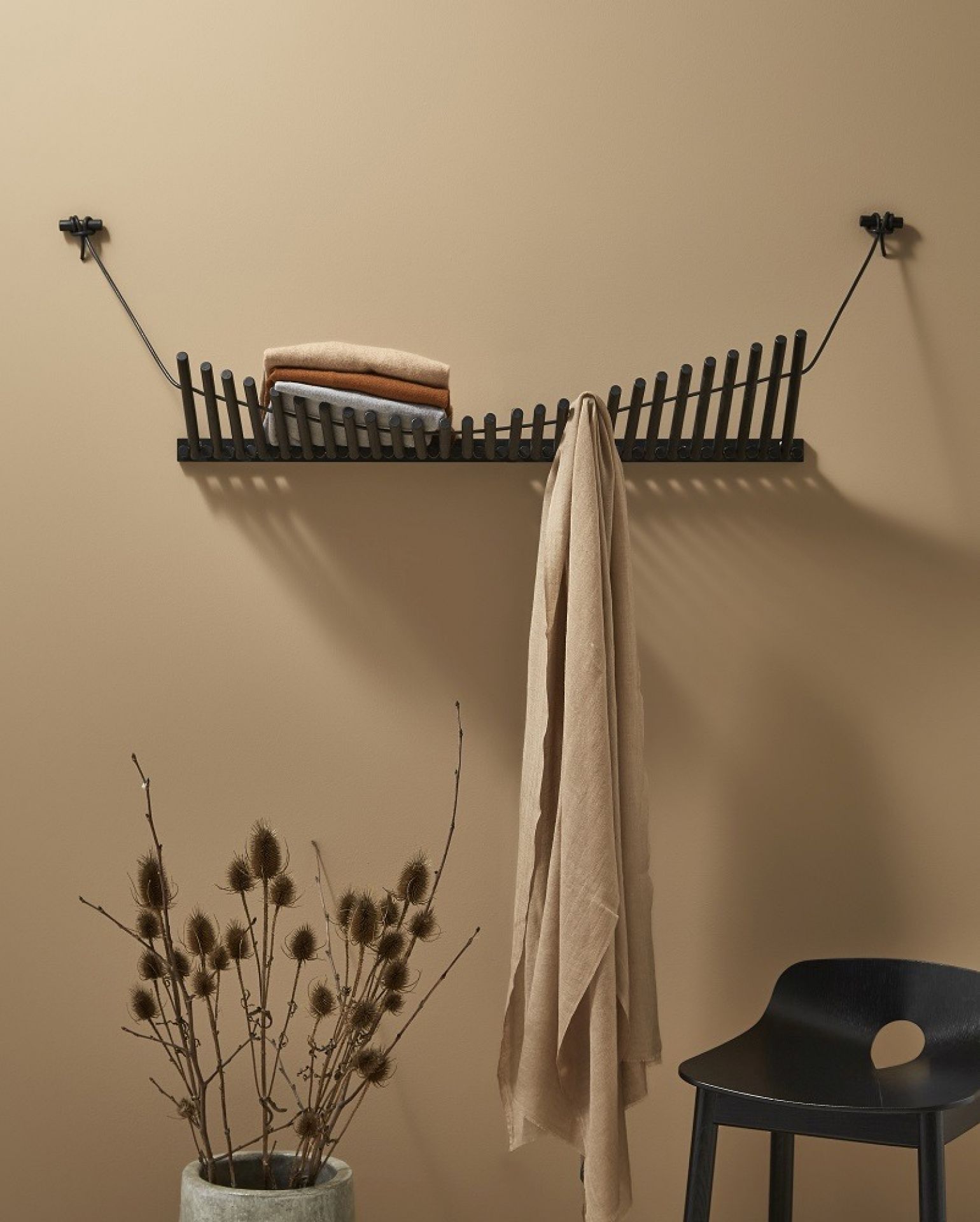 Knaegt Coat Rack Wandgarderobe von Woud in Eiche schwarz mit Kleidung und Dekoration.