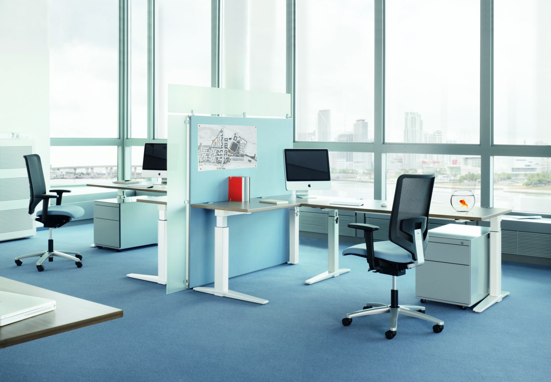 Büro mit mehreren TALO.S Schreibtischen von König+Neurath, Bürostühlen, Containern und großen Fenstern mit Blick auf die Stadt.