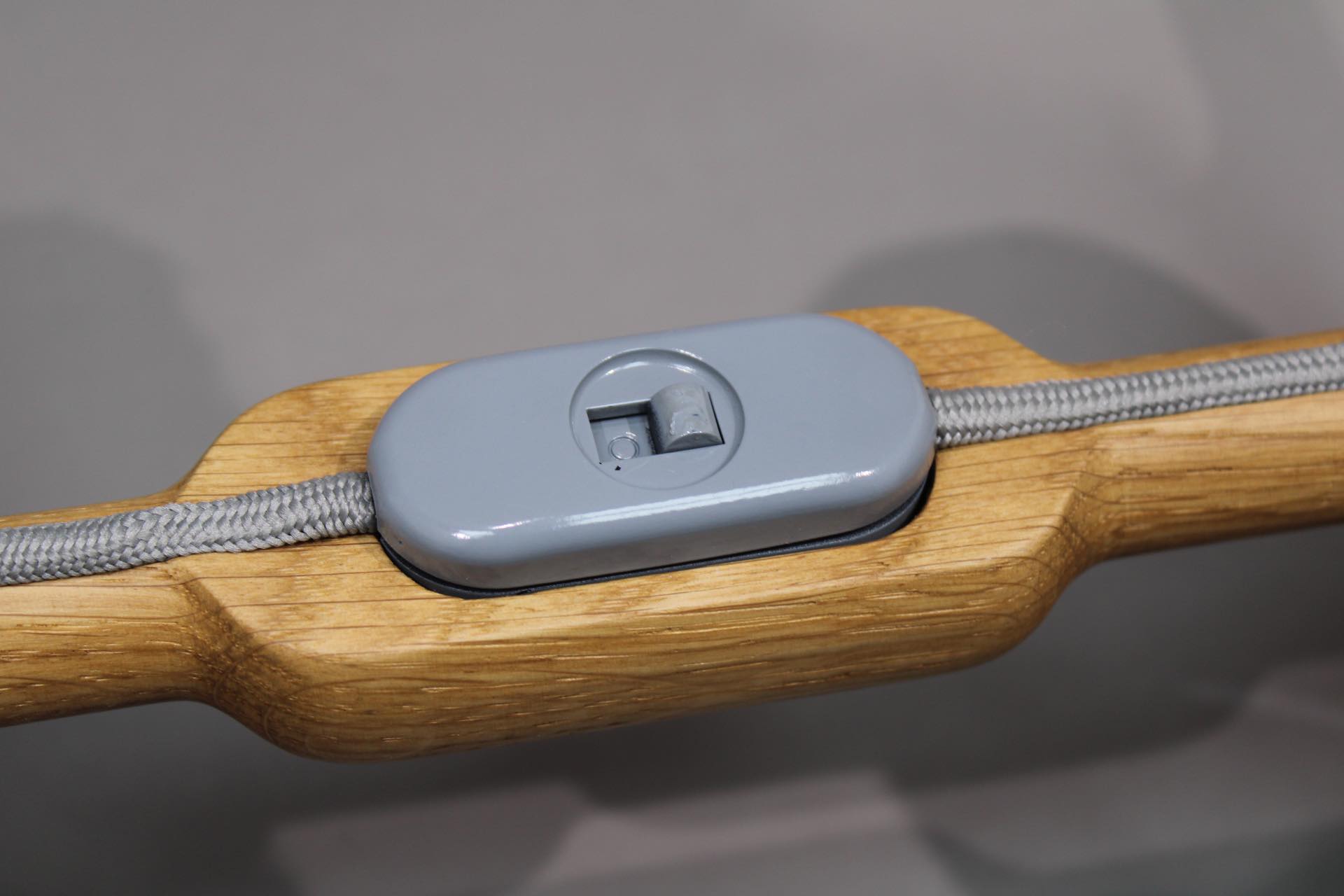 Detailaufnahme: Grauer Schalter der Granny Tischleuchte auf Holzsockel mit Textilkabel.