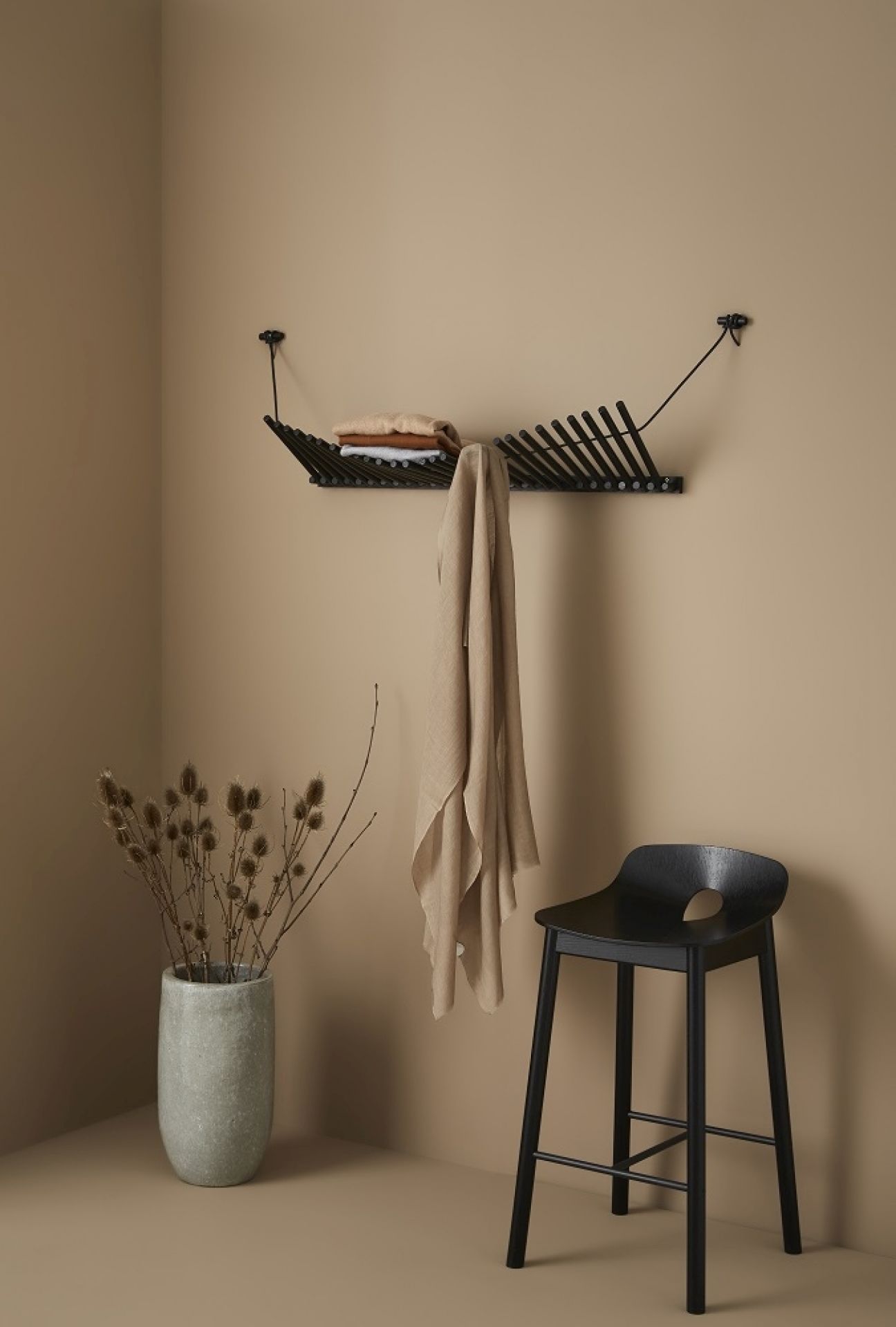 Knaegt Wandgarderobe von Woud in Schwarz: Moderne Garderobe aus Eiche mit Kleidung und Ablage.