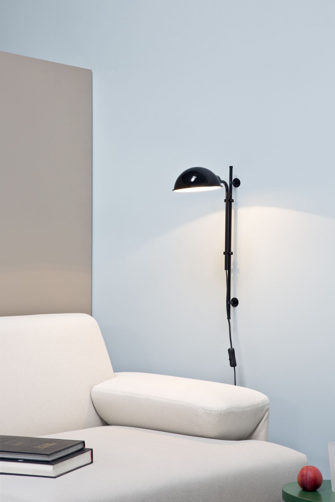 Funiculí A Wandleuchte von Marset, perlweiße Wandlampe neben einem Sofa. Designleuchte für Wohnzimmer.