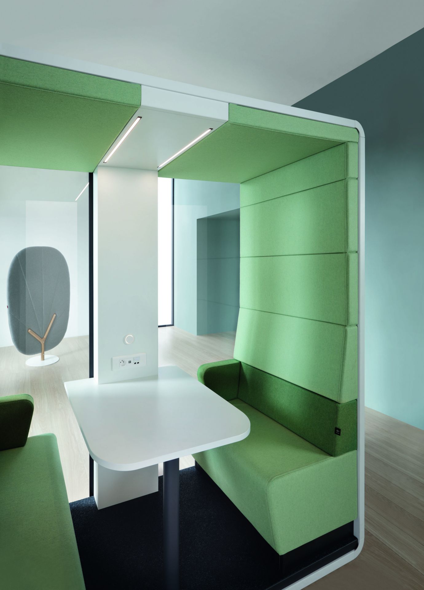 HushMeet.Open Meetingbox: Offener Besprechungsraum mit Tisch, grünen Polstern und integrierter Beleuchtung für moderne Büros.