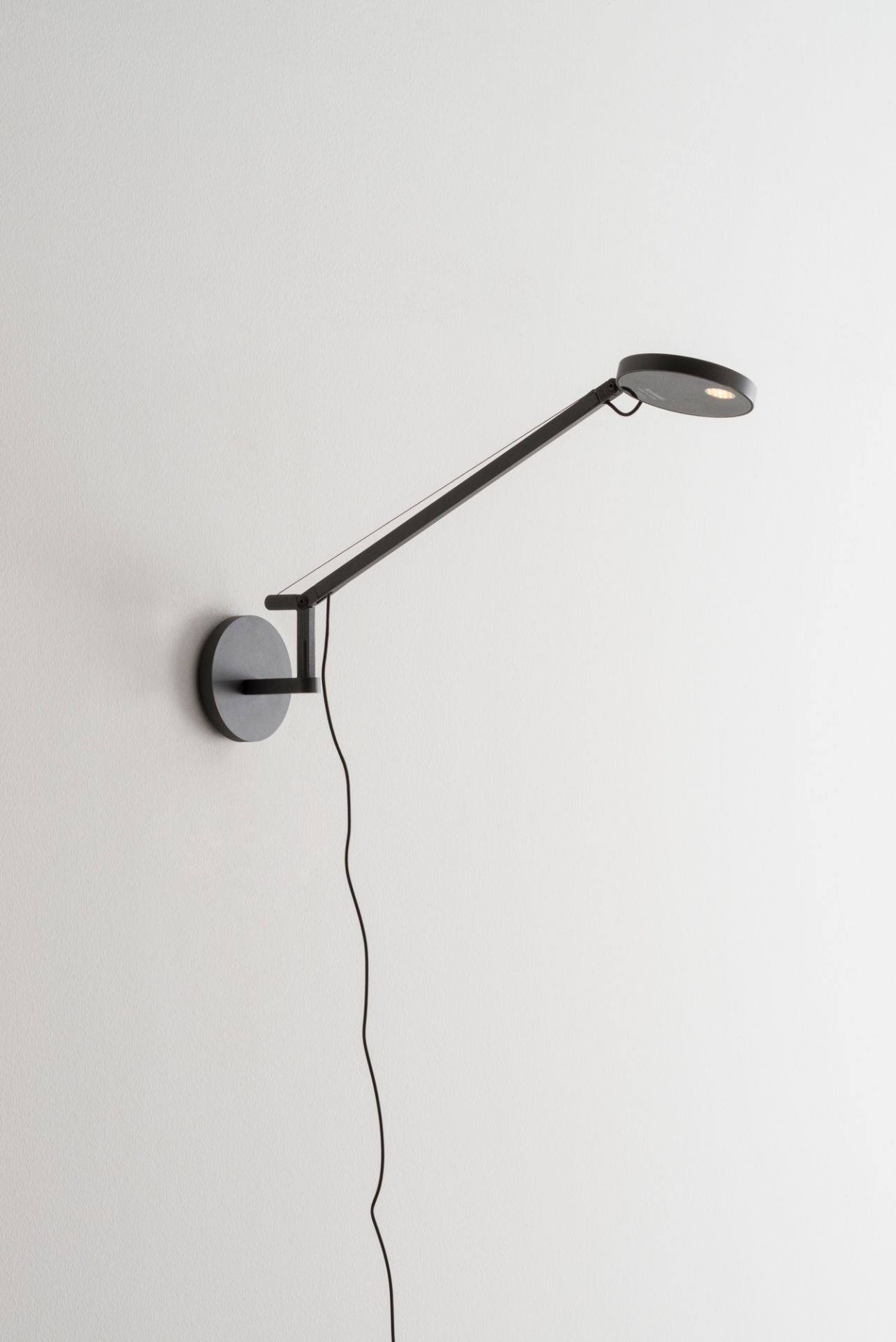 Schwarze Demetra Micro Wandleuchte von Artemide mit verstellbarem Arm und warmweißem Licht (2700K).