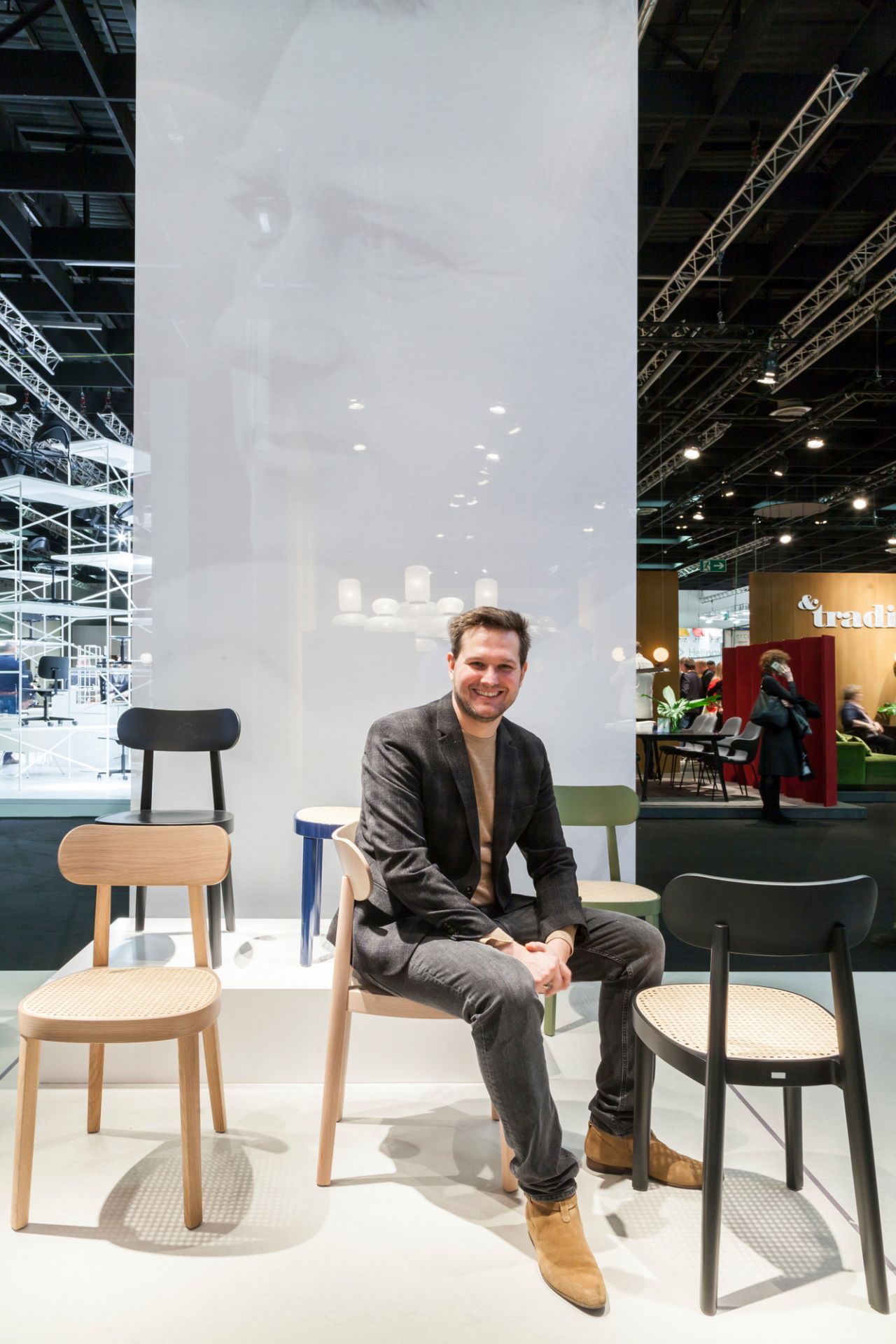 Mann sitzt auf einem hellen Holzstuhl, Modell 118 M von Thonet, weiß lasiert.