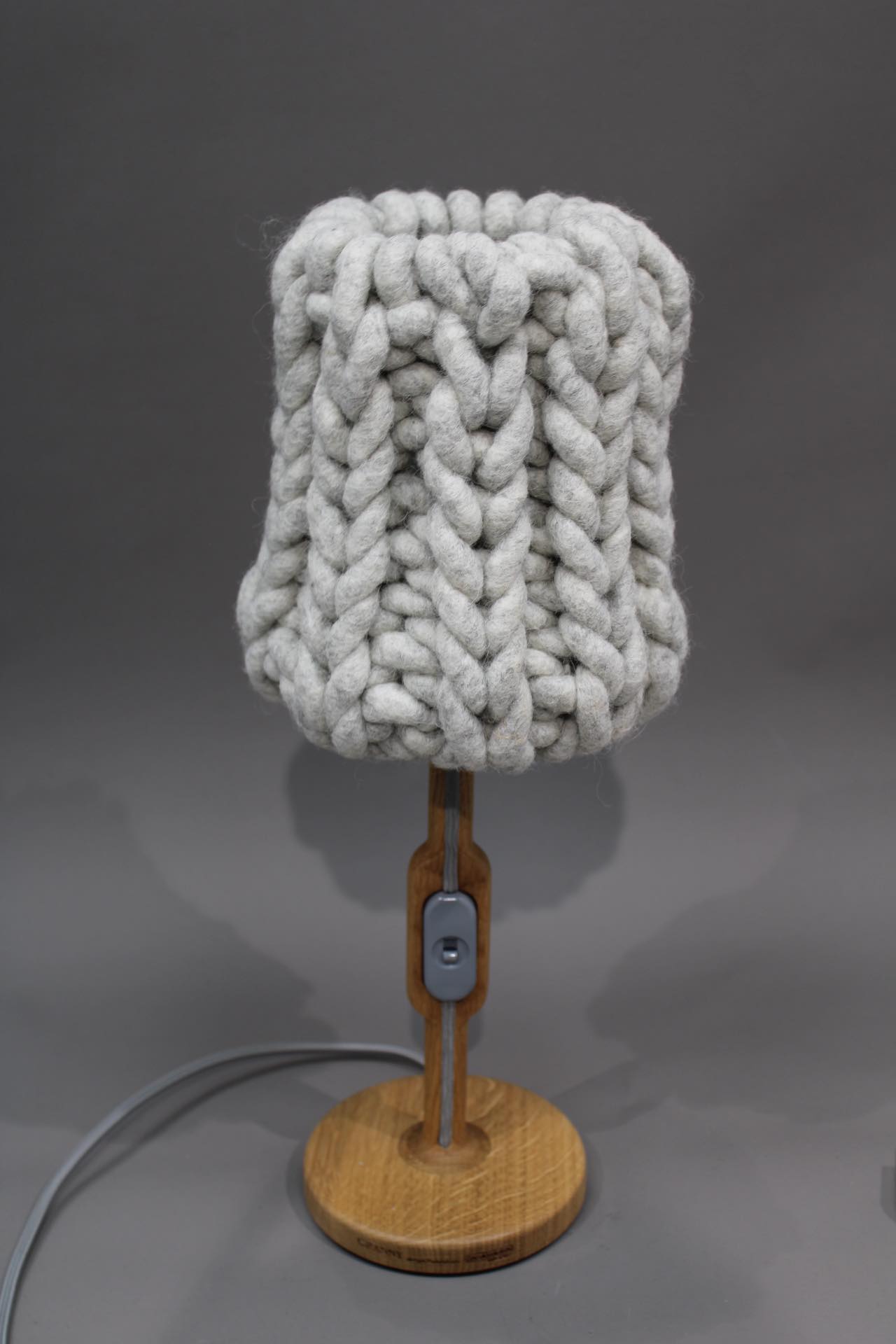 Graue Granny Tischleuchte mit gestricktem Lampenschirm und Holzfuß, modernes Design für Wohnzimmer.