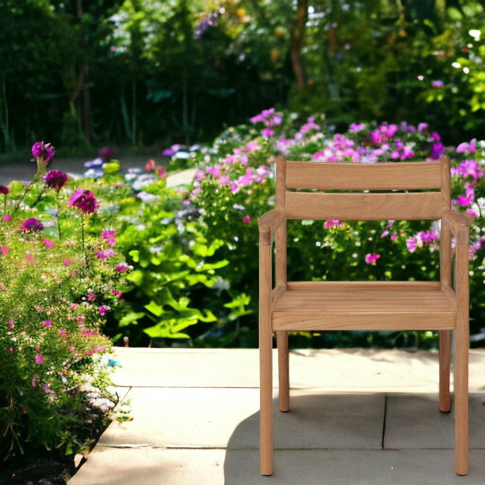 Jack Outdoor Stuhl aus Teakholz mit Armlehnen vor blühendem Garten. Gartenmöbel für den Außenbereich.