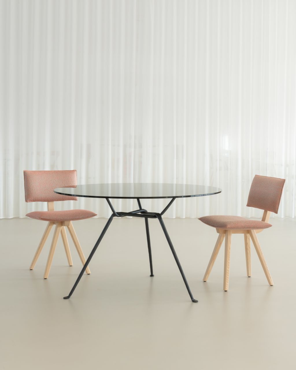 Zwei Trave Upholstered Chair Stühle von Magis mit einem runden Tisch vor einem weißen Vorhang.