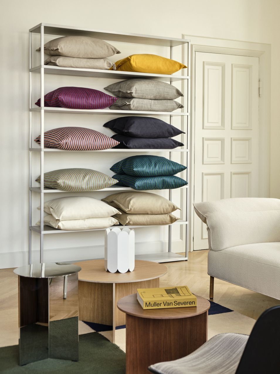 Regal mit gestapelten Ribbon Kissen von Hay in verschiedenen Farben und Mustern. Dekorative Kissen für Wohnzimmer.