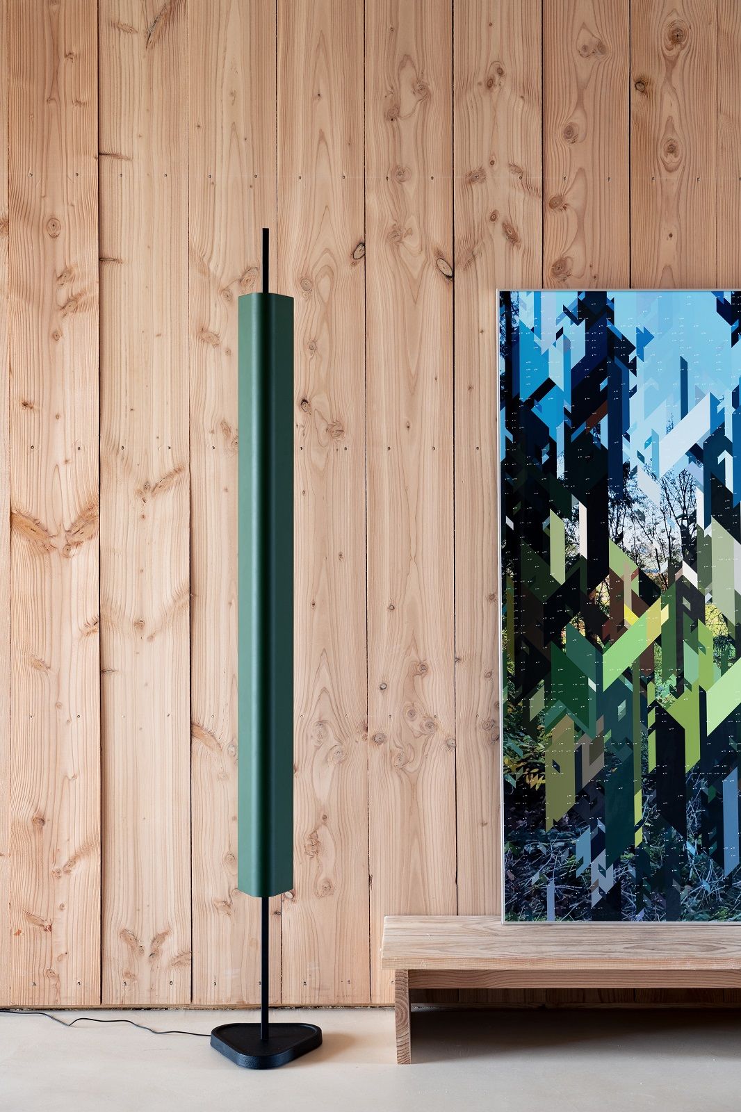 Emi Floor Stehleuchte von Flos: Moderne, grüne Stehlampe mit minimalistischem Design vor Holzwand und Kunstwerk.