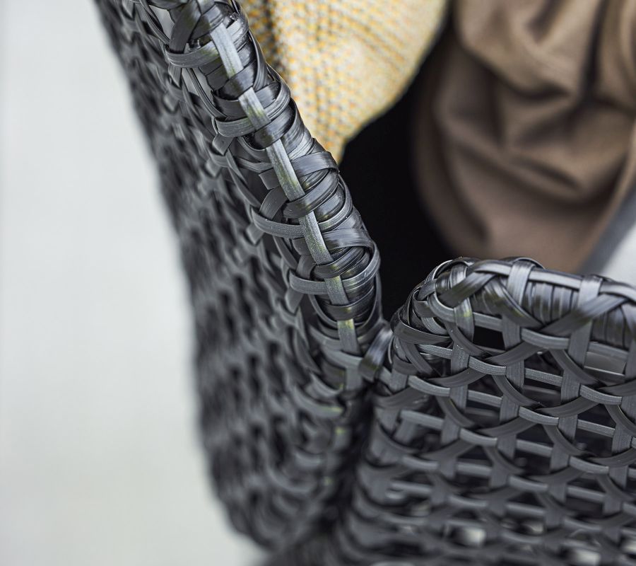 Detailaufnahme des Cane-Line Vibe Highbacksessels in Schwarz, mit Kissen, Fokus auf das Flechtmuster.